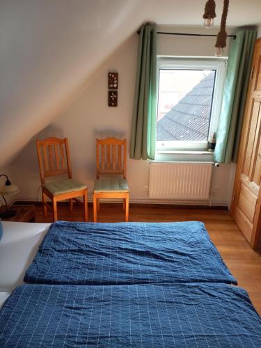 ダゲビュルにあるHaus Strand-Gutのベッドルーム1室(ベッド1台、椅子2脚、窓付)