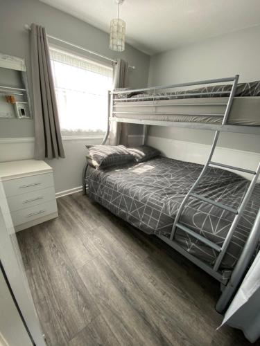 a bedroom with a bunk bed and a wooden floor at East Coast Chalets 57 at California Sands in Scratby