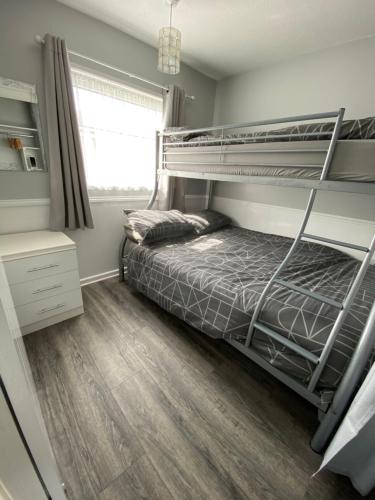 East Coast Chalets 57 at California Sands في Scratby: غرفة نوم مع سرير بطابقين وأرضية خشبية