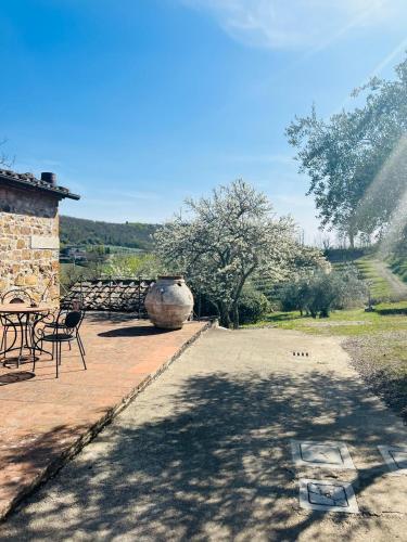 a patio with a large vase and a table and chairs at LOCANDA PODERE LE VIGNE in Radda in Chianti
