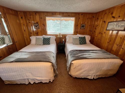 two beds in a room with wooden walls at Mountain View Lodge in Red River