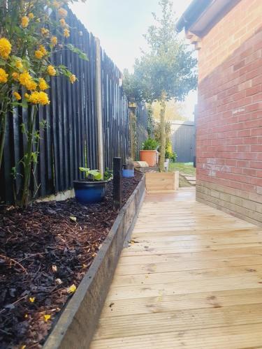 a garden with a wooden walkway next to a fence at Little Lupin in Loddon