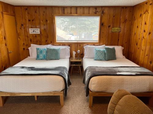two beds in a room with wooden walls at Mountain View Lodge in Red River