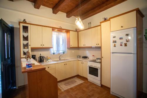 a kitchen with white appliances and wooden cabinets at Aggelina's House by GuestCorfu in Kynopiástai
