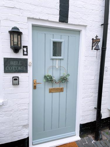 Bell Cottage right in the heart of Bridgnorth في بريدغنورث: باب أزرق على مبنى أبيض مع علامة