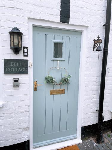 a blue door on a white building with a sign at Beautiful Bell Cottage Heart of Bridgnorth Walk Everywhere in Bridgnorth