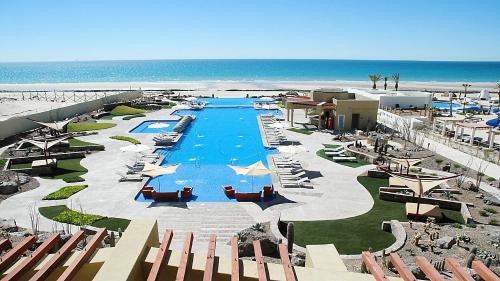 a resort with a large swimming pool and the beach at Encanto Living Two Bedroom Unit by Kivoya in Puerto Peñasco