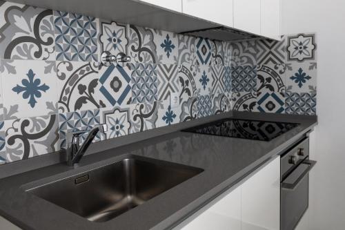 uma cozinha com pia e azulejos azuis e brancos em Ajuda - Apartments em Lisboa