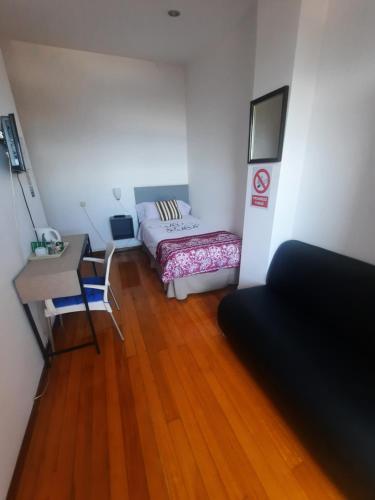 um quarto com uma cama, uma secretária e uma mesa em Hospedaje Lopez em La Coruña