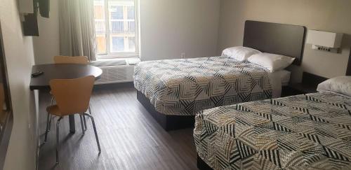 a hotel room with two beds and a table and chairs at Motel 6 Mobile, AL - Airport Blvd in Mobile
