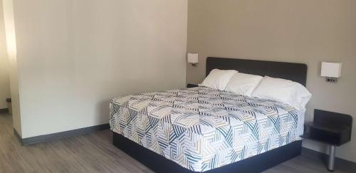 a bedroom with a bed with a white and blue comforter at Motel 6 Mobile, AL - Airport Blvd in Mobile