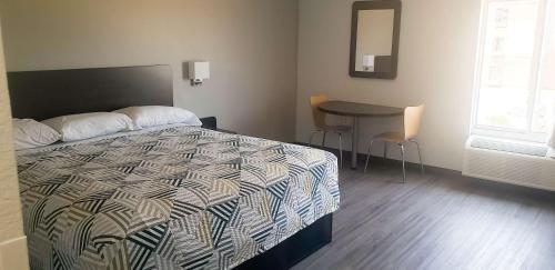 a bedroom with a bed and a table in it at Motel 6 Mobile, AL - Airport Blvd in Mobile
