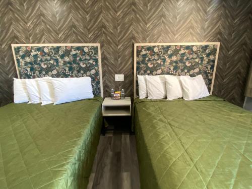 duas camas verdes sentadas uma ao lado da outra num quarto em Harbor Inn em Harbor City