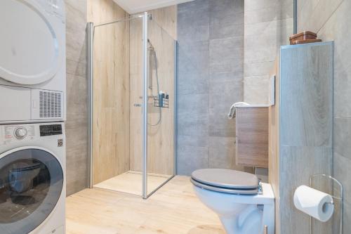 a bathroom with a toilet and a shower at Luxe appartement dichtbij strand en zee, in het hart van de bollenstreek in Noordwijkerhout