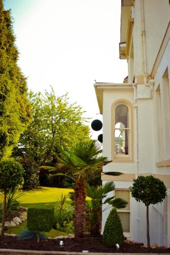 a house with a palm tree in front of a yard at Washington House Hotel in Bournemouth
