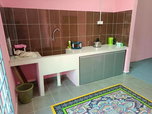 een kleine keuken met een aanrecht in een roze kamer bij Homestay Machang Sentral in Macang