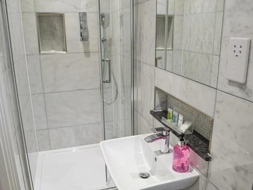 y baño blanco con lavabo y ducha. en Serenity Lodge Otterburn en Otterburn