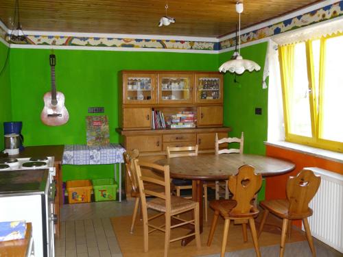 uma cozinha com paredes verdes e uma mesa e cadeiras de madeira em Sonnenhof in Ziemetshausen bei Legoland Günzburg em Ziemetshausen
