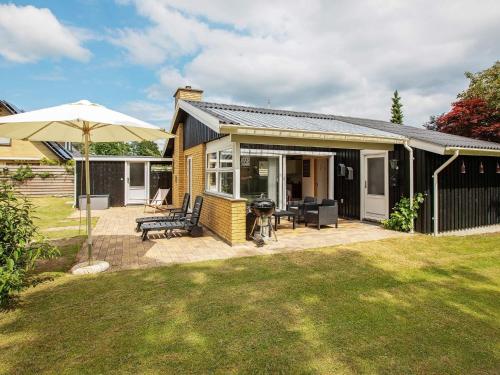 a house with a patio and an umbrella at 5 person holiday home in Væggerløse-By Traum in Marielyst
