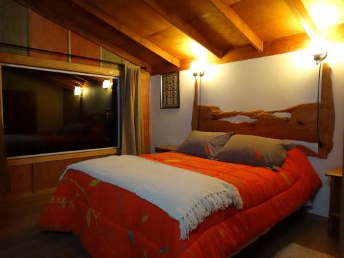 a bedroom with a bed with an orange blanket at Cabañas Tranquihue Llifen in llifen