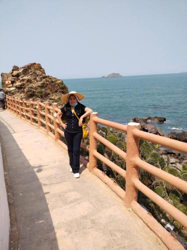 a woman walking down a path next to the ocean at Anh Quân Hotel in Quy Nhon