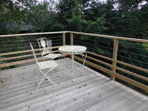 two chairs and a table on a wooden deck at B&B Les Tilleuls in Vielsalm