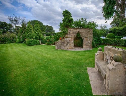 a garden with a stone arch in the middle of a lawn at Rogerthorpe Manor Hotel in Pontefract