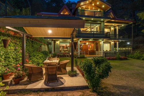 a house with a table and chairs in a yard at StayVista at Floradale W Jacuzzi & Wood-Fire Pizza in Kasauli