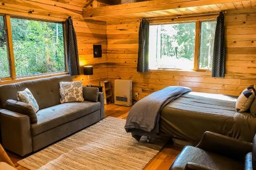 Cove Cabin Retreat في Shelter Cove: غرفة نوم بسرير واريكة ونوافذ