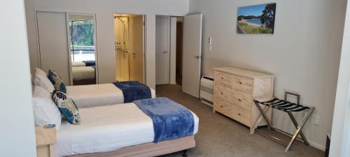 a bedroom with two beds and a dresser and a mirror at Quality Hotel Oceans Tutukaka in Tutukaka