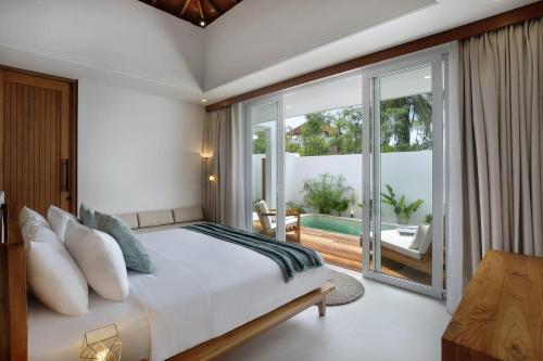 a bedroom with a king sized bed and a balcony at Neptune Studios Lombok in Kuta Lombok