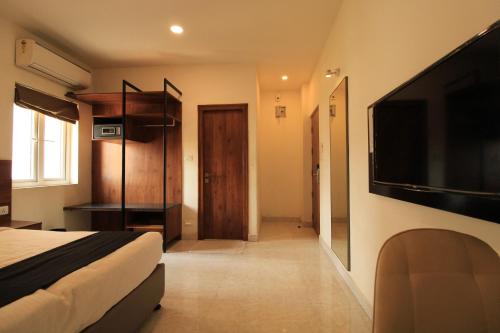 a bedroom with a bed and a flat screen tv at Arunaa Inn Airport Hotel,Chennai in Chennai