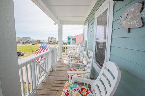 a porch with rocking chairs and an american flag at Life's A Beach in Holden Beach