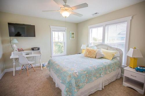 a bedroom with a bed and a desk and a ceiling fan at Life's A Beach in Holden Beach