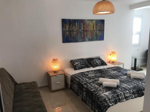 a bedroom with two beds and a couch and two lamps at Villa Nissi Beach 28 in Ayia Napa