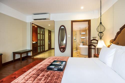 a bedroom with a bed and a mirror and a bathroom at Hanoi La Siesta Hotel & Spa in Hanoi