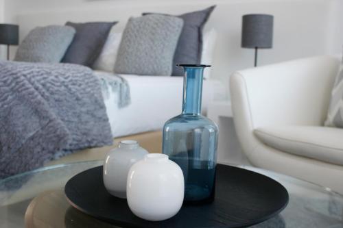 a glass bottle and two white vases on a table in a living room at Swakopmund Luxury Suites in Swakopmund