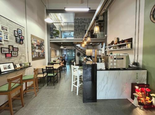 a restaurant with a counter and tables and chairs at Hybrit hostel&cafe in Hat Yai