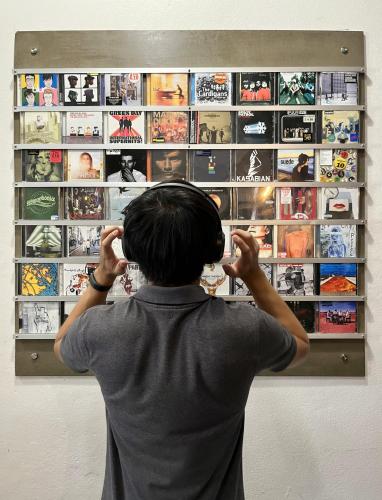 a woman looking at a display of video games at Hybrit hostel&cafe in Hat Yai