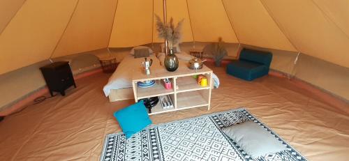 Tente Bell au camping Hautoreille في Bannes: خيمة بسرير وطاولة وكرسي