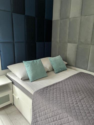 łóżko z dwoma niebieskimi poduszkami na górze w obiekcie Domek SunRelax z jacuzzi niedaleko Suntago w mieście Korytów