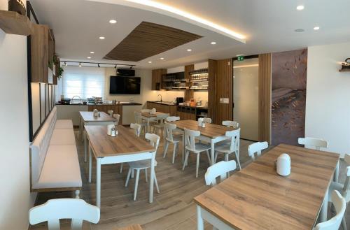 a restaurant with wooden tables and white chairs at Žigon Bed & Breakfast in Logatec