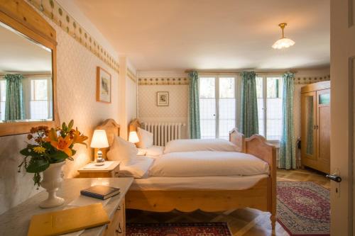 a bedroom with a bed and a desk and windows at Historic Hotel Falken in Wengen