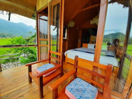 a bedroom with a bed and two chairs on a deck at Little Mai Chau Home Stay in Mai Châu