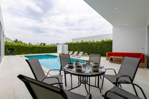a patio with a table and chairs next to a pool at Modern 4 Bedroom Pool Villa KH-A5 in Khao Tao