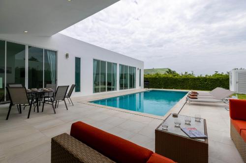 a patio with a pool and a table and chairs at Modern 4 Bedroom Pool Villa KH-A5 in Khao Tao