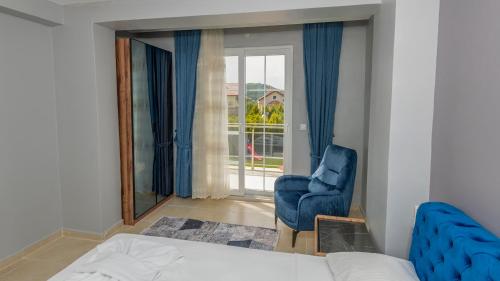 a bedroom with a bed and a chair and a window at Blue - 4 Bedroom Holiday Villa in Hisarönü in Oludeniz