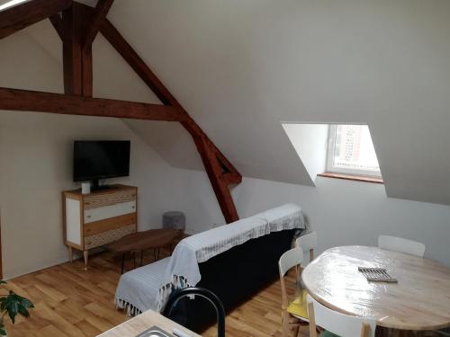 a room with a bed and a table and a tv at La Plage in Fécamp
