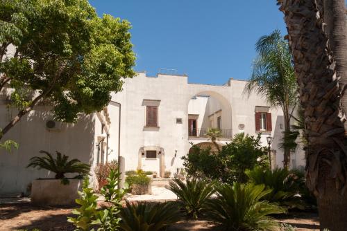 a white building with trees and plants in front of it at Palazzo Francesco Grassi in Aradeo