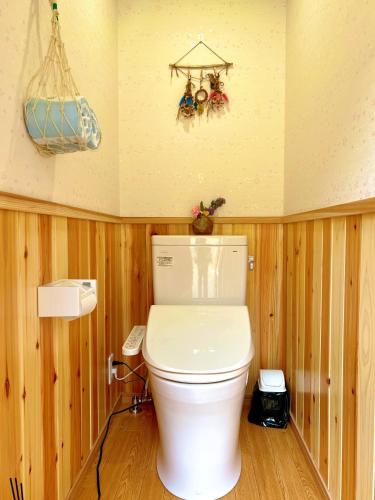 a bathroom with a toilet in a room with wooden walls at 和心村ー古民家とグランピングと自然森山川海 in Minato